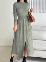 Woman wearing a green mock neck long sleeve knit midi dress with pleated skirt, front buttons and slit.