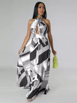 Woman wearing a geometric black and white patterned dress holding a green handbag on a gray background