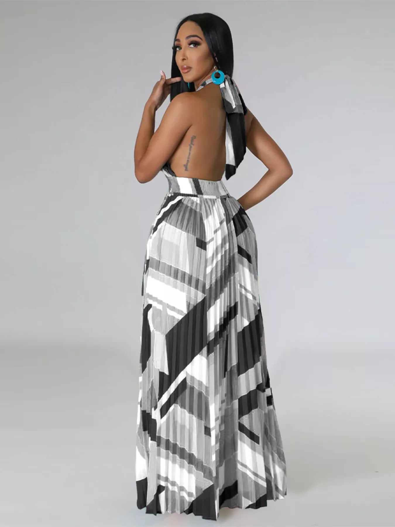 Woman wearing a black and white geometric patterned dress on a gray background
