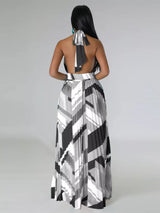 Woman wearing a black and white patterned halter neck dress on a plain background