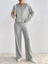 Woman wearing the Honey Drawstring Ribbed Hoodie and Straight Leg Pants Set in light gray with white sneakers, cozy ribbed two-piece lounge set from Chic Mystik Boutique.