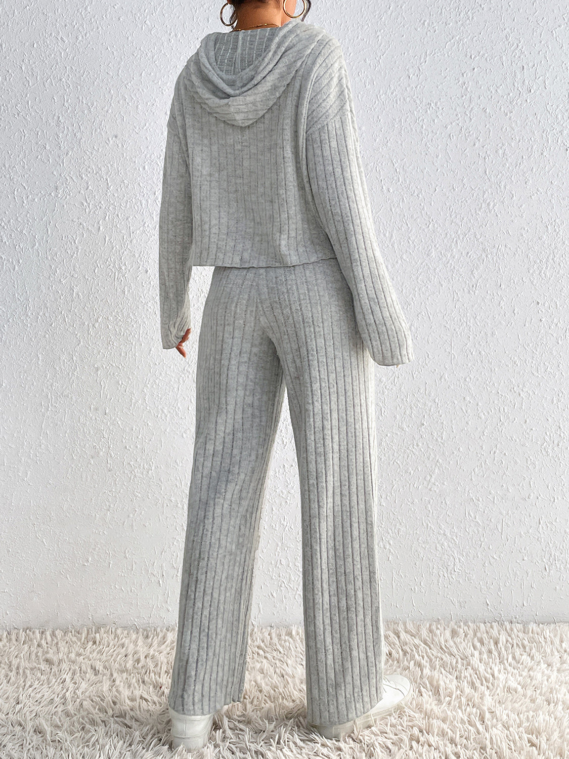 Woman wearing the Honey Drawstring Ribbed Hoodie and Straight Leg Pants Set in light gray with white sneakers, cozy ribbed two-piece lounge set from Chic Mystik Boutique.