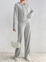 Woman wearing the Honey Drawstring Ribbed Hoodie and Straight Leg Pants Set in light gray with white sneakers, cozy ribbed two-piece lounge set from Chic Mystik Boutique.