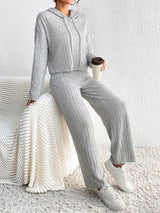 Woman wearing the Honey Drawstring Ribbed Hoodie and Straight Leg Pants Set in light gray with white sneakers, cozy ribbed two-piece lounge set from Chic Mystik Boutique.