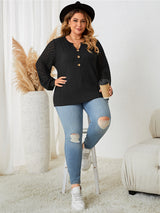 Woman wearing a black top with mesh sleeves and ripped jeans in a home setting.