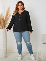 Woman wearing a black long-sleeve top and blue jeans in a minimalistic room.