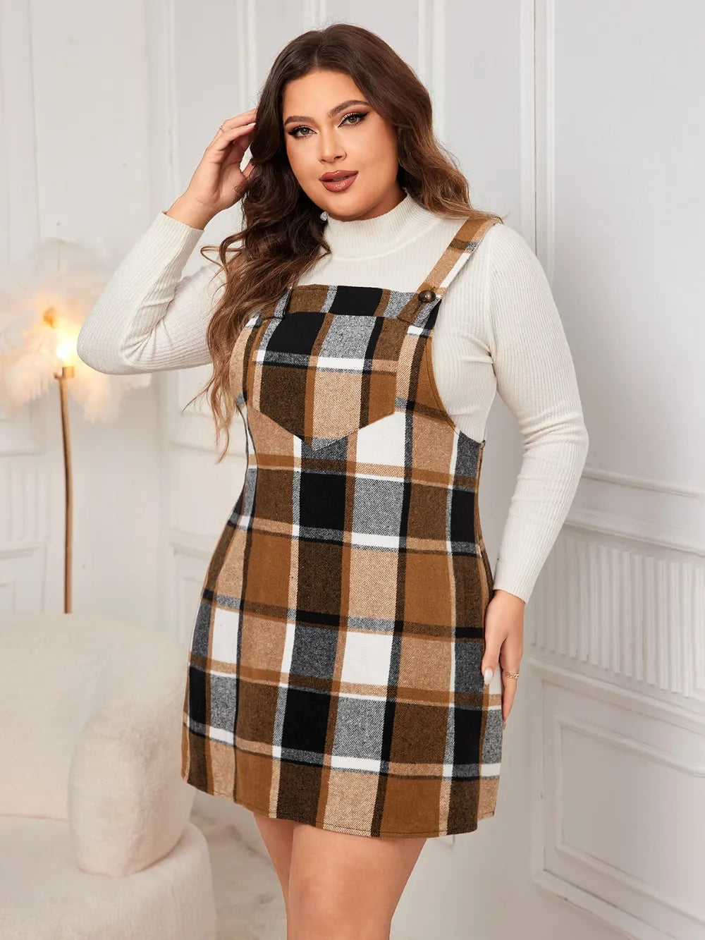 Woman wearing the Honey Plus Size Plaid Wide Strap Overall Dress layered over a cream mock neck sweater with a black felt hat, stylish plus size plaid fall dress from Chic Mystik Boutique.