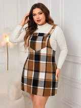 Woman wearing the Honey Plus Size Plaid Wide Strap Overall Dress layered over a cream mock neck sweater with a black felt hat, stylish plus size plaid fall dress from Chic Mystik Boutique.
