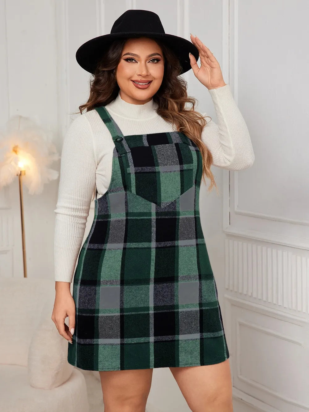 Woman wearing the Honey Plus Size Plaid Wide Strap Overall Dress layered over a cream mock neck sweater with a black felt hat, stylish plus size plaid fall dress from Chic Mystik Boutique.