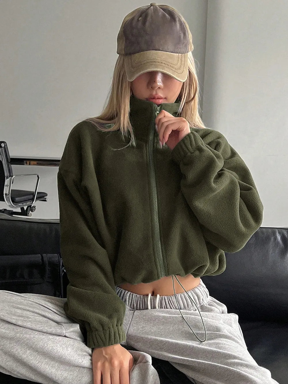 Woman wearing the Honey Zip Up Long Sleeve Cropped Jacket in olive green with joggers and a baseball cap, lightweight cropped fall jacket available at Chic Mystik Boutique.