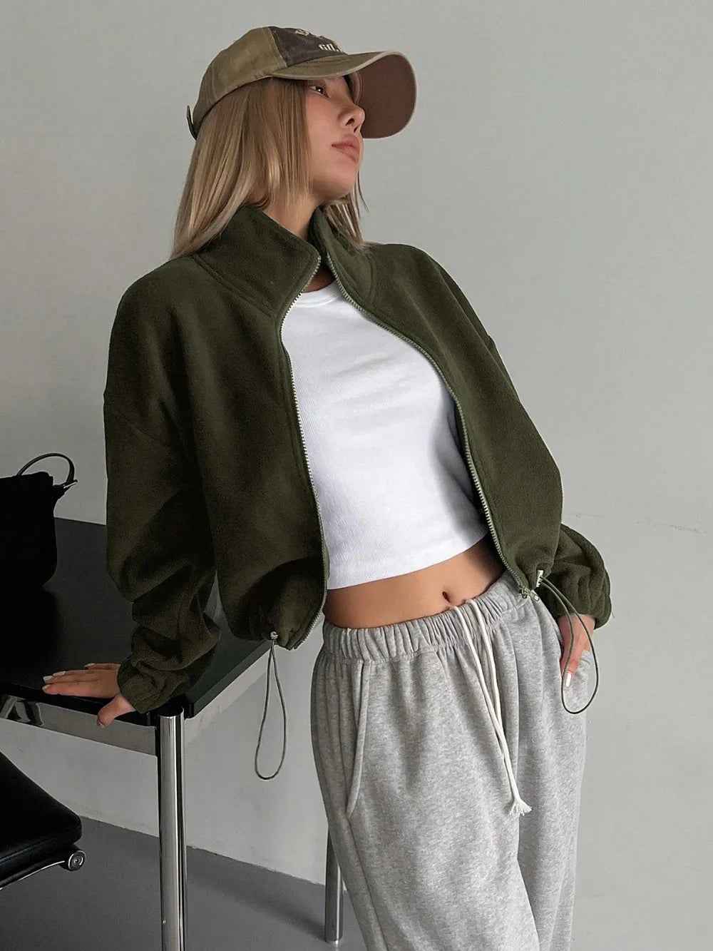 Woman wearing the Honey Zip Up Long Sleeve Cropped Jacket in olive green with joggers and a baseball cap, lightweight cropped fall jacket available at Chic Mystik Boutique.