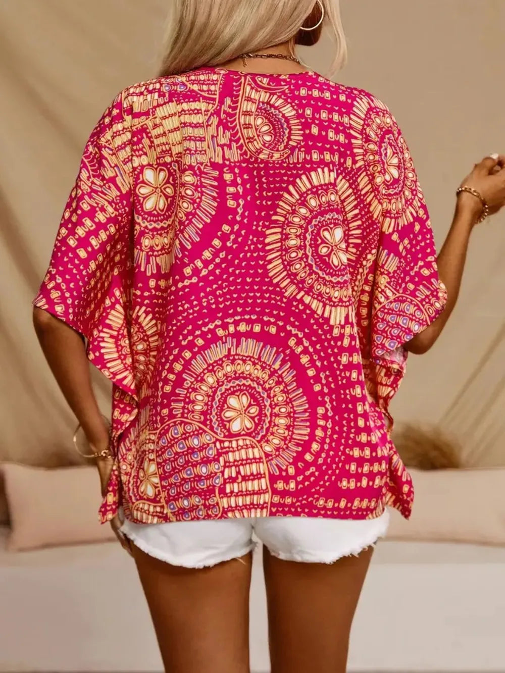 Hot pink printed V-neck top with half sleeves and a relaxed boho-inspired fit paired with white shorts.