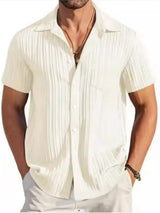 Man wearing a ivory textured short sleeve button-up shirt with white pants for a polished casual summer look.
