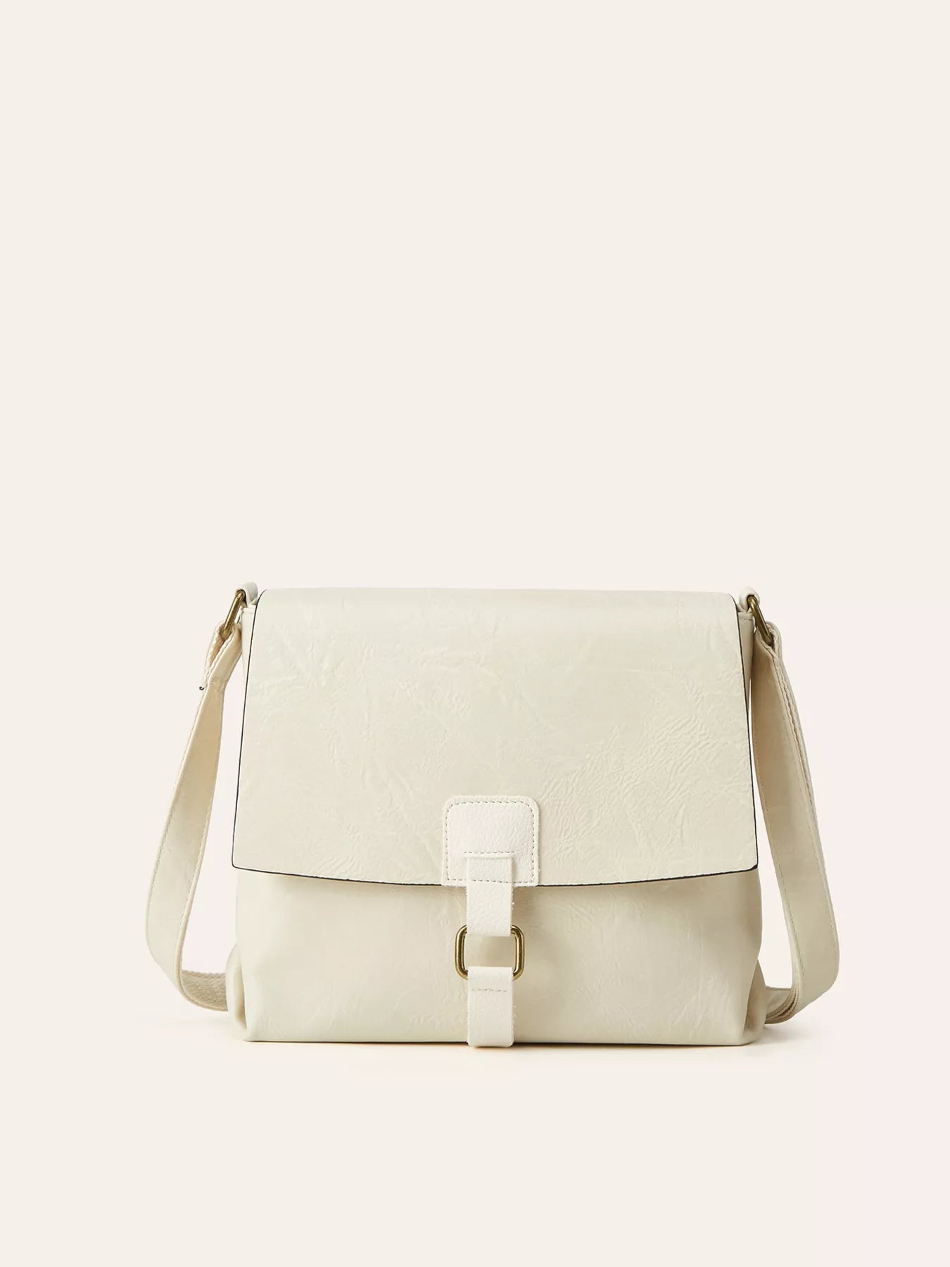 Ivory vintage-style crossbody bag featuring a flap closure, decorative buckle detail, and adjustable shoulder strap.