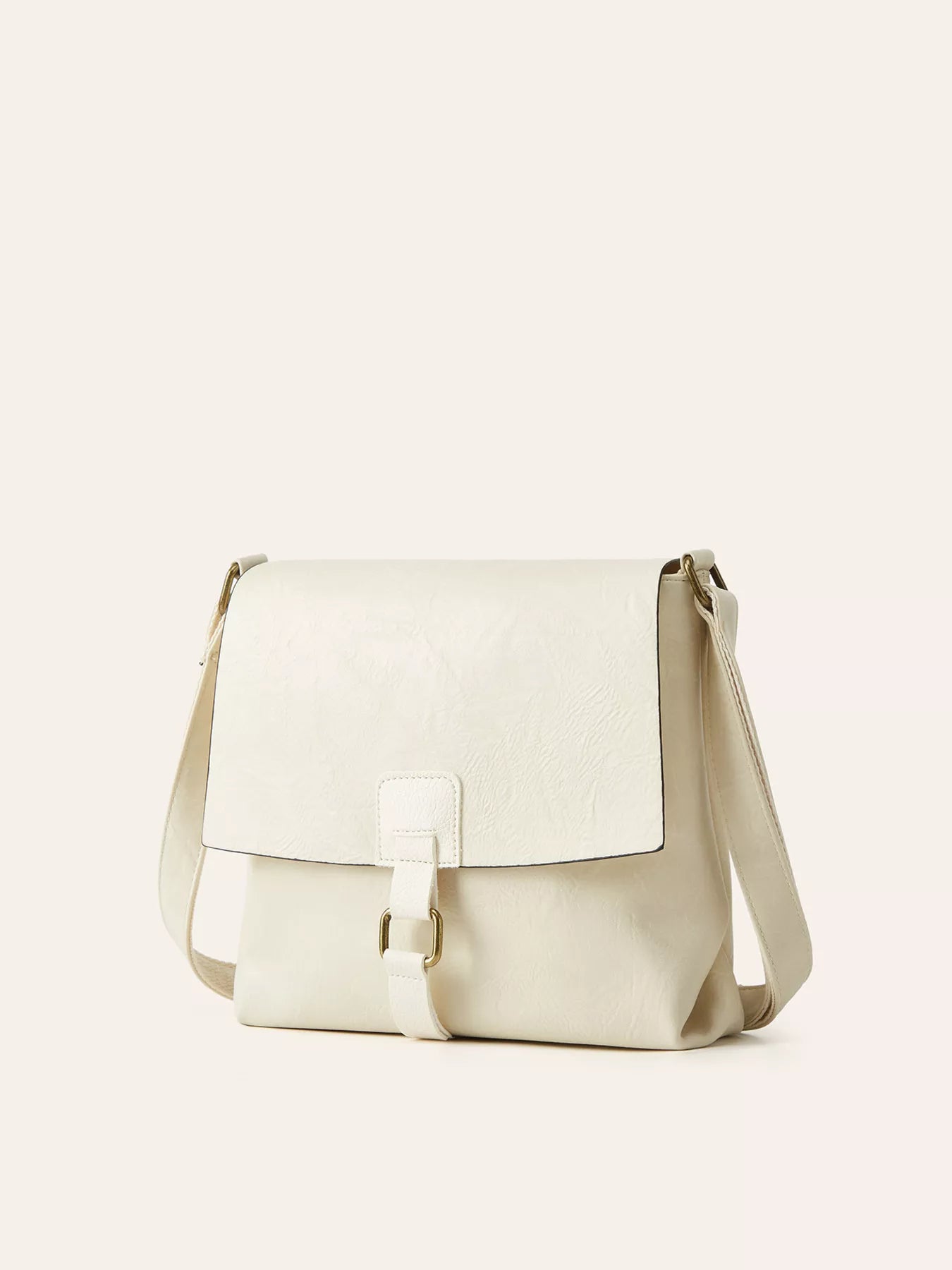 Ivory vintage-style crossbody bag featuring a flap closure, decorative buckle detail, and adjustable shoulder strap.