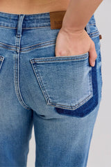 Judy Blue Full Size Mid Rise BF Patch & Repair Destroy Release Hem Jeans in medium wash featuring distressed detailing, boyfriend fit, raw release hem, and slightly stretchy denim for casual everyday style.