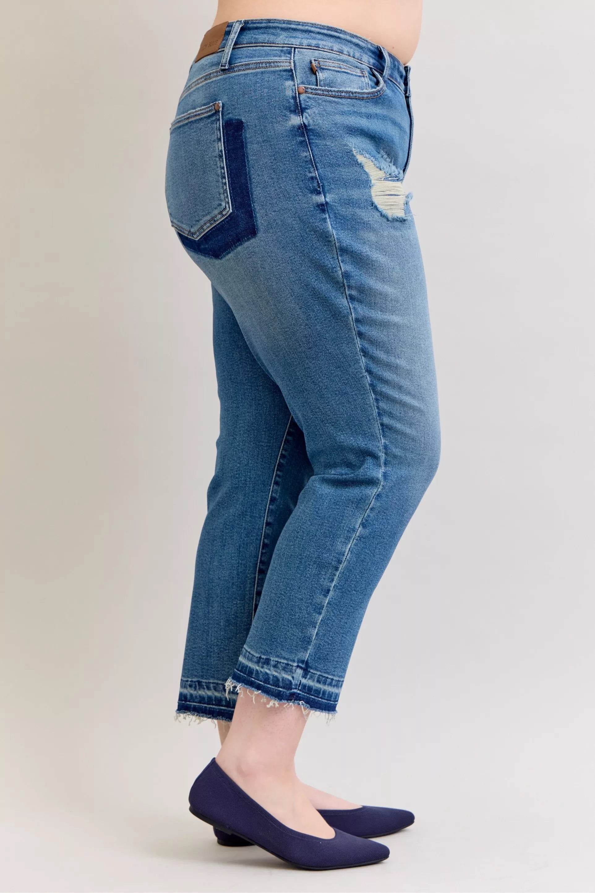 Judy Blue Full-Size Mid-Rise BF Patch & Repair Destroy Release Hem Jeans in medium wash featuring distressed detailing, boyfriend fit, raw release hem, and slightly stretchy denim for casual everyday style.
