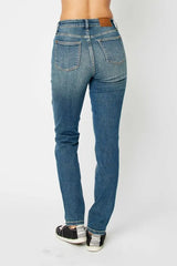 Model wearing Judy Blue high-waist skinny jeans in a medium wash with oversized front pockets and a slim, ankle-length fit, paired with black sneakers.