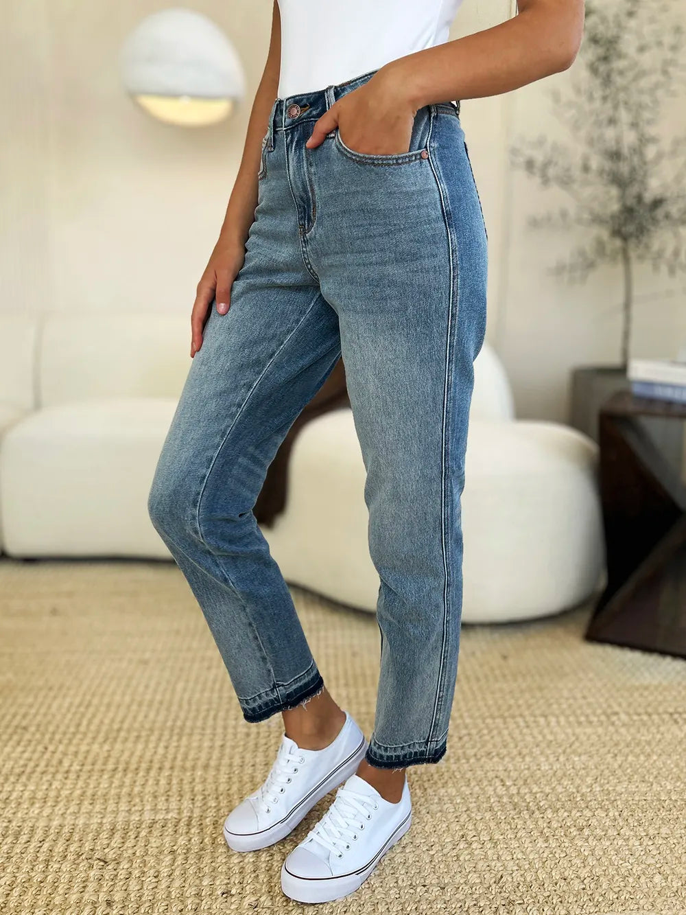 Judy Blue Full Size Mid Rise Rigid Magic Release Hem Jeans in medium wash featuring a flattering mid-rise fit, straight-leg silhouette, moderate stretch, and trendy raw release hem, styled with white sneakers.