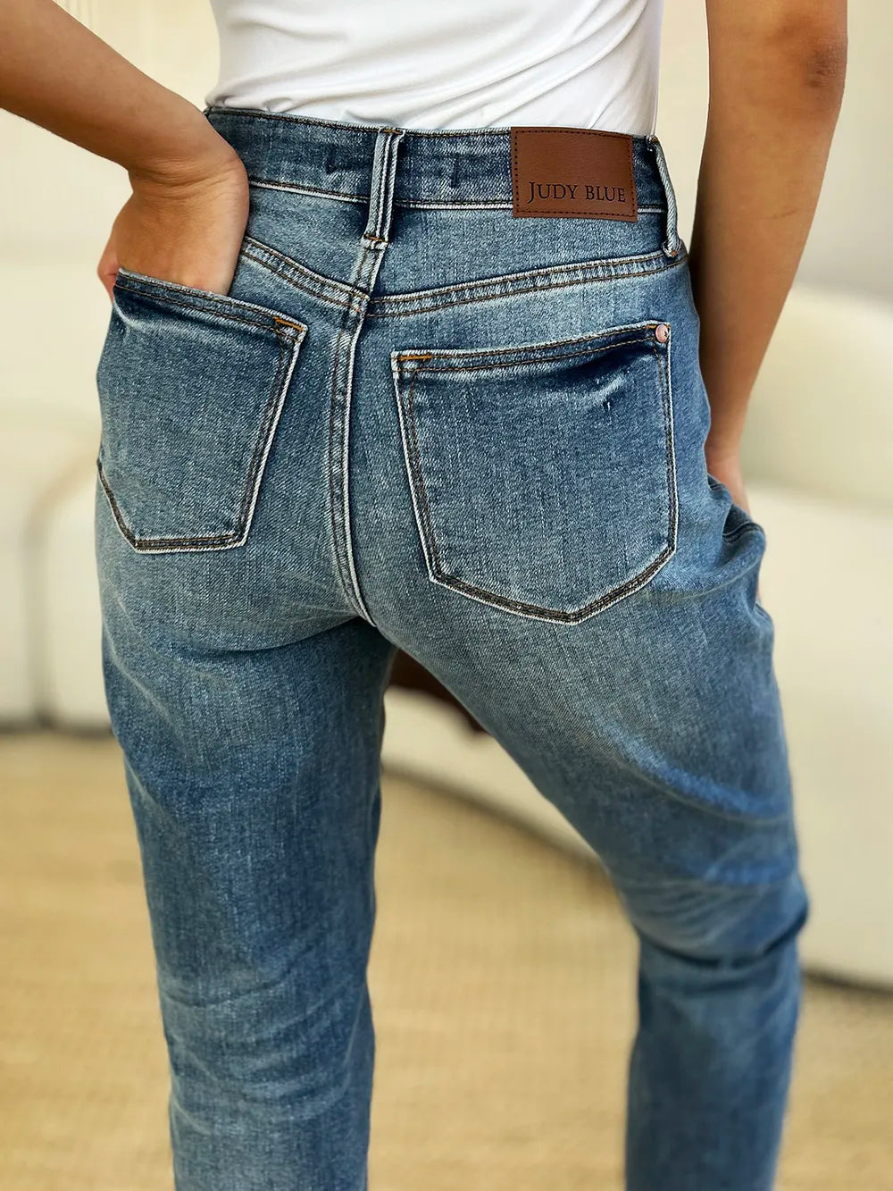 Judy Blue Full Size Mid Rise Rigid Magic Release Hem Jeans in medium wash featuring a flattering mid-rise fit, straight-leg silhouette, moderate stretch, and trendy raw release hem, styled with white sneakers.