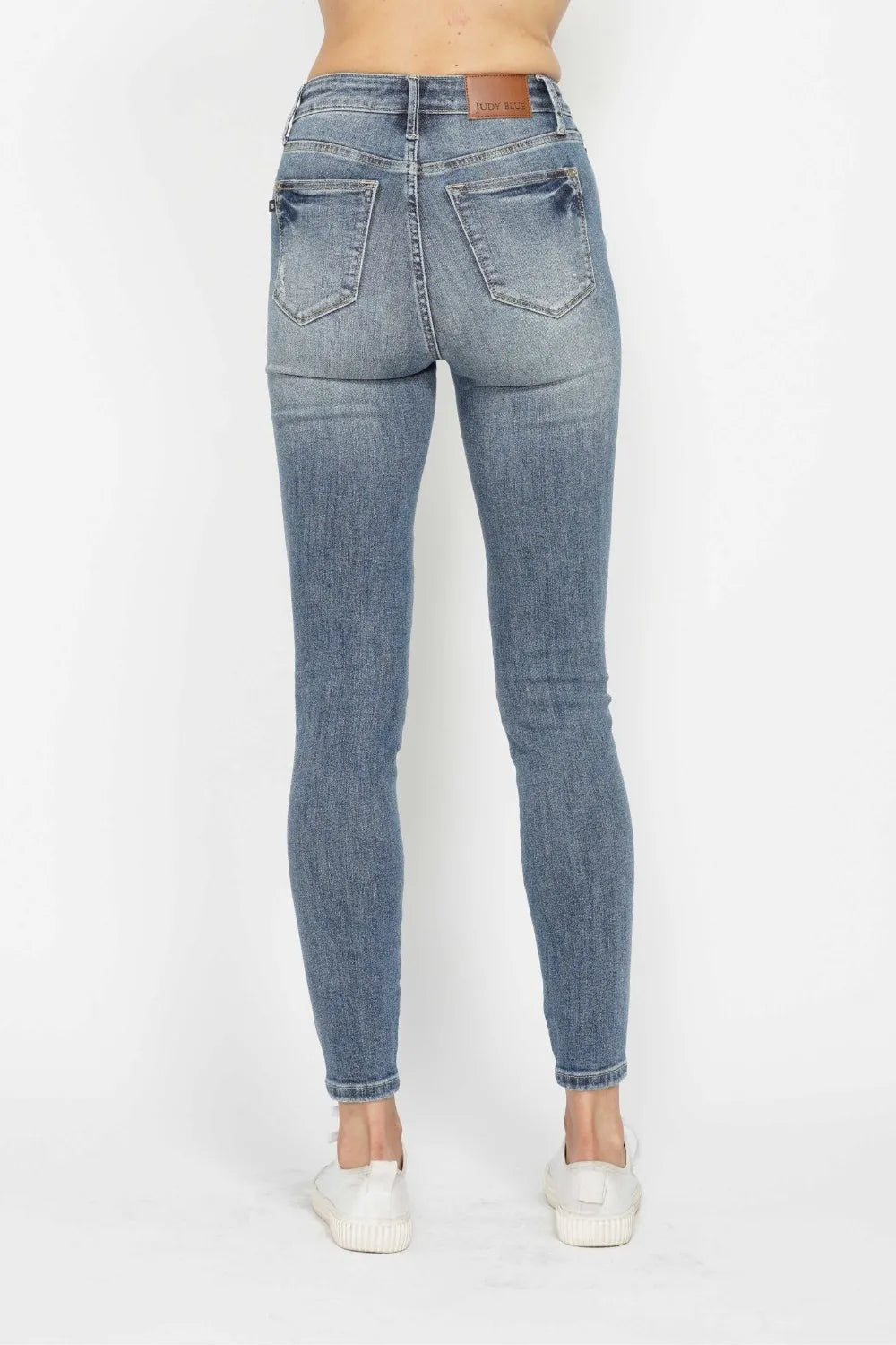 Woman wearing Judy Blue high-rise tummy control contrast wash skinny jeans with a flattering skinny-leg fit and light medium wash denim.