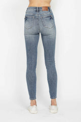 Woman wearing Judy Blue high-rise tummy control contrast wash skinny jeans with a flattering skinny-leg fit and light medium wash denim.
