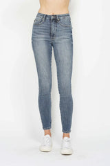 Woman wearing Judy Blue high-rise tummy control contrast wash skinny jeans with a flattering skinny-leg fit and light medium wash denim.