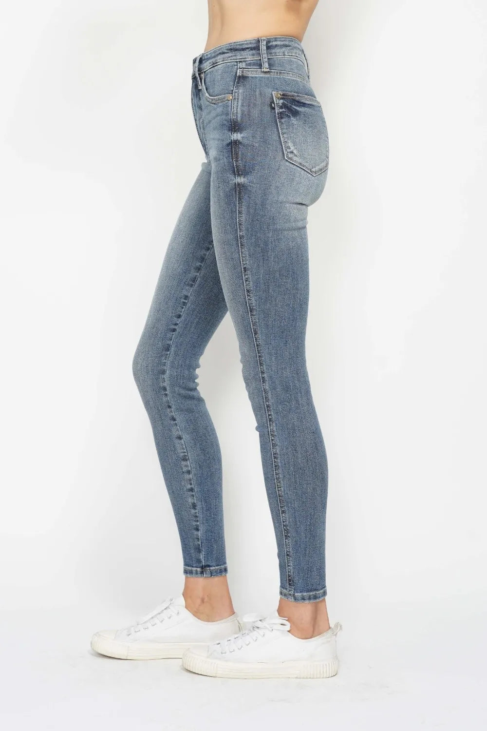 Woman wearing Judy Blue high-rise tummy control contrast wash skinny jeans with a flattering skinny-leg fit and light medium wash denim.