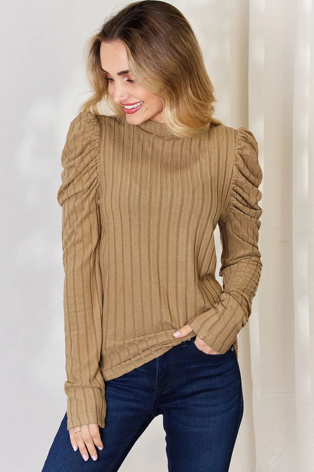 Woman wearing a khaki Basic Bae ribbed mock neck long sleeve top with ruched puff shoulders, paired with dark blue jeans.