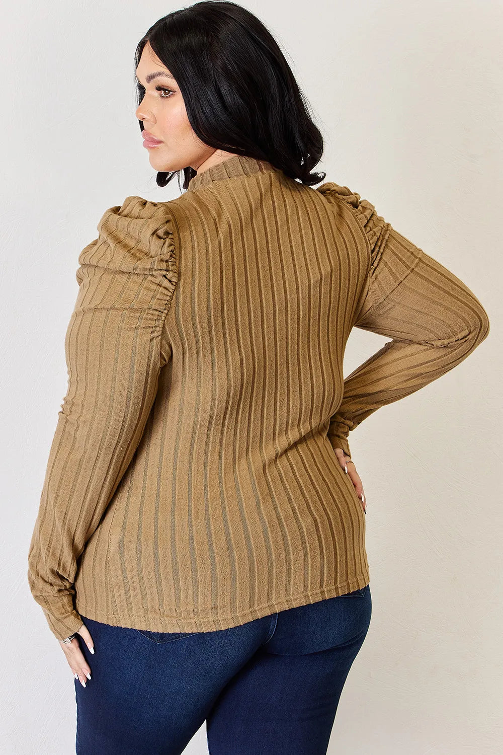 Woman wearing a khaki Basic Bae ribbed mock neck long sleeve top with ruched puff shoulders, paired with dark blue jeans.