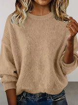 Woman wearing a khaki round neck dropped shoulder sweater with dark-wash jeans.