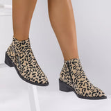 Woman wearing khaki leopard-print ankle boots with block heels and side zipper details.
