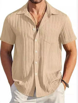 Man wearing a khaki textured short sleeve button-up shirt with white pants for a polished casual summer look.