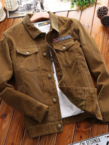 Men's khaki button-up long sleeve jacket with collared neckline, chest flap pockets, and textured fabric, displayed over a white graphic T-shirt.