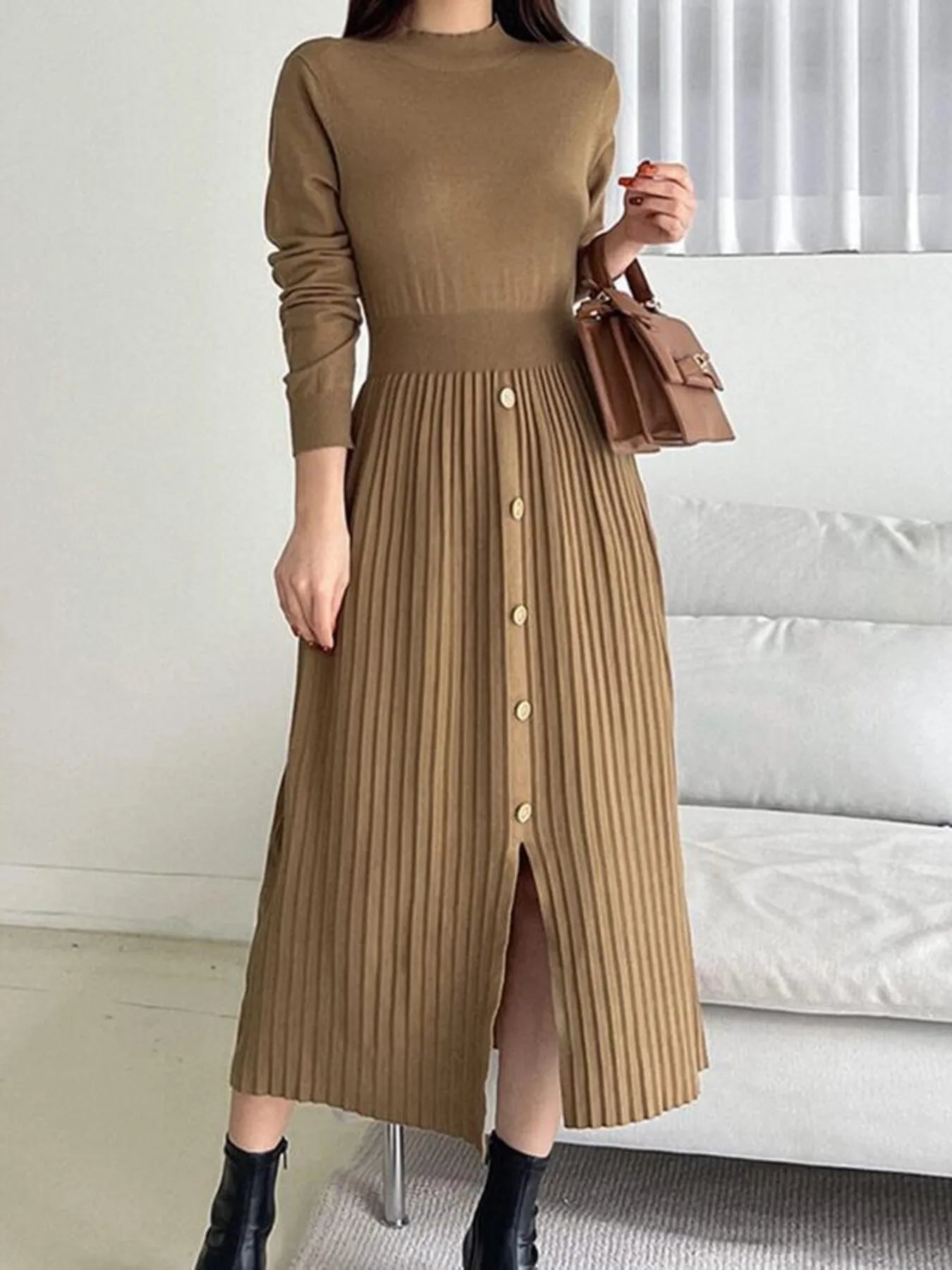 Woman wearing a khaki mock neck long sleeve knit midi dress with pleated skirt, front buttons and slit.