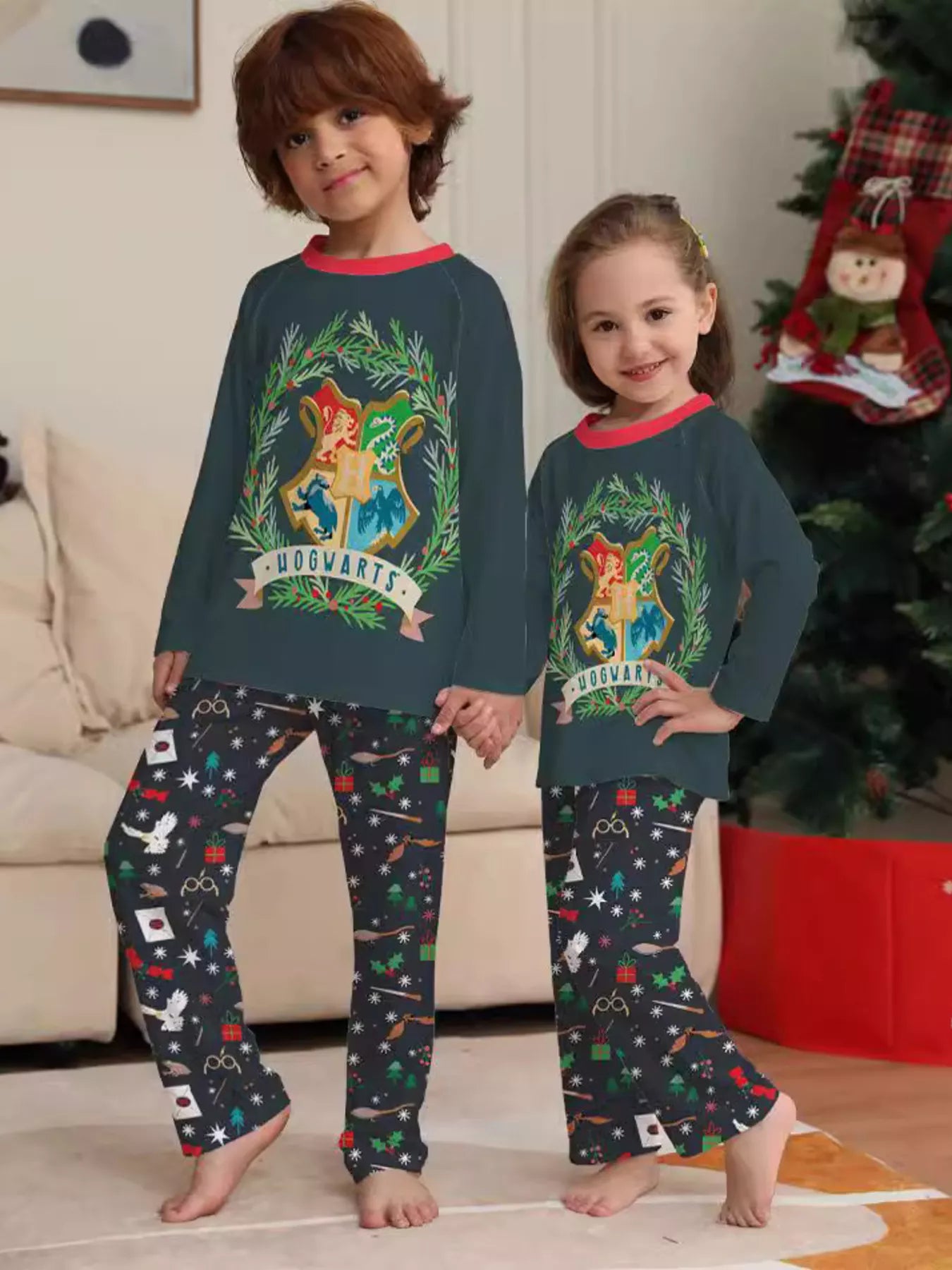 Family wearing matching dark green Hogwarts graphic Christmas pajama tops with coordinating navy holiday print pajama pants.