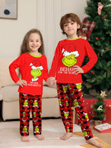 Boy and girl wearing red Grinch-themed Christmas pajama sets with green character graphics and coordinating red plaid holiday pants.