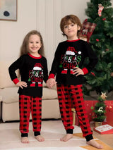 Boy and girl wearing matching Christmas Crew graphic pajama sets with black long-sleeve tops and red buffalo plaid pants.