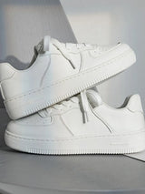 Pair of white sneakers on a light gray background