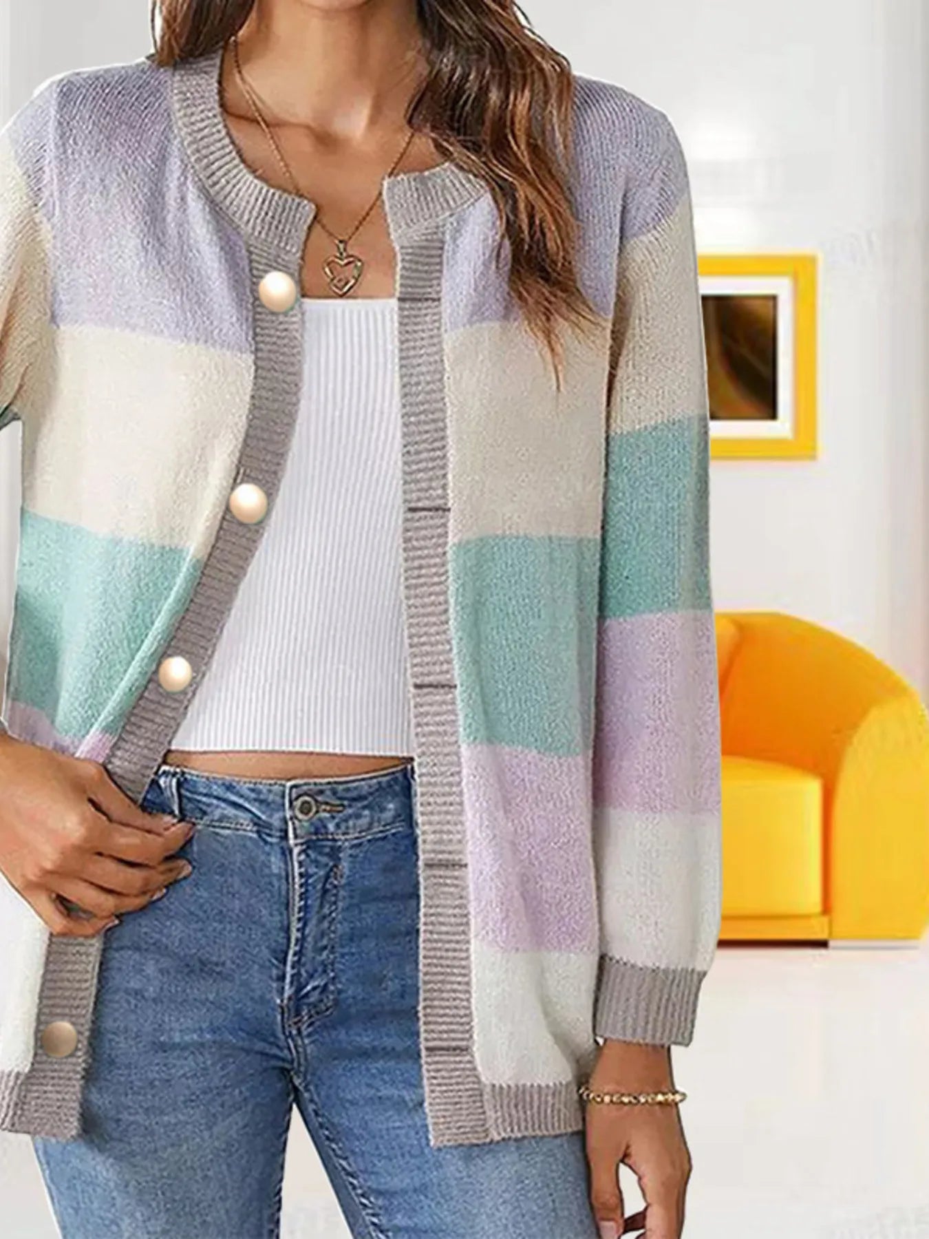 Women's lavender, light green, and cream color block knit cardigan with round neckline, button-front closure, and ribbed trim, styled with a white top and blue jeans.