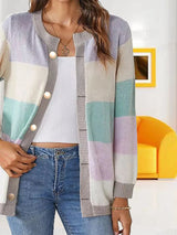 Women's lavender, light green, and cream color block knit cardigan with round neckline, button-front closure, and ribbed trim, styled with a white top and blue jeans.