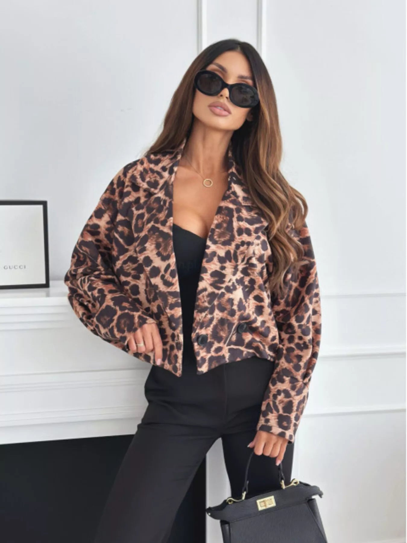 Woman wearing a brown and tan leopard print cropped button blazer styled with a black top and black pants.