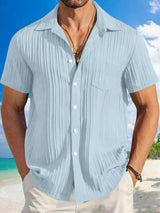Man wearing light blue textured short sleeve button-up shirt with white pants for a polished casual summer look.