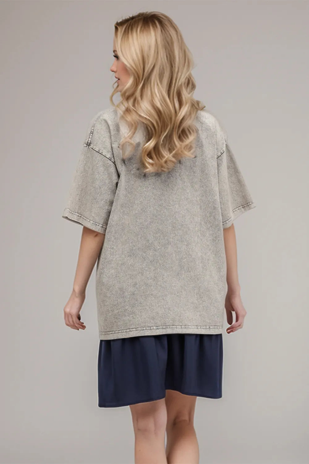 Woman wearing an oversized light gray Basic Bae round-neck half-sleeve T-shirt styled with dark denim jeans and a long pendant necklace for a relaxed, casual look.