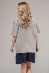 Woman wearing an oversized light gray Basic Bae round-neck half-sleeve T-shirt styled with dark denim jeans and a long pendant necklace for a relaxed, casual look.