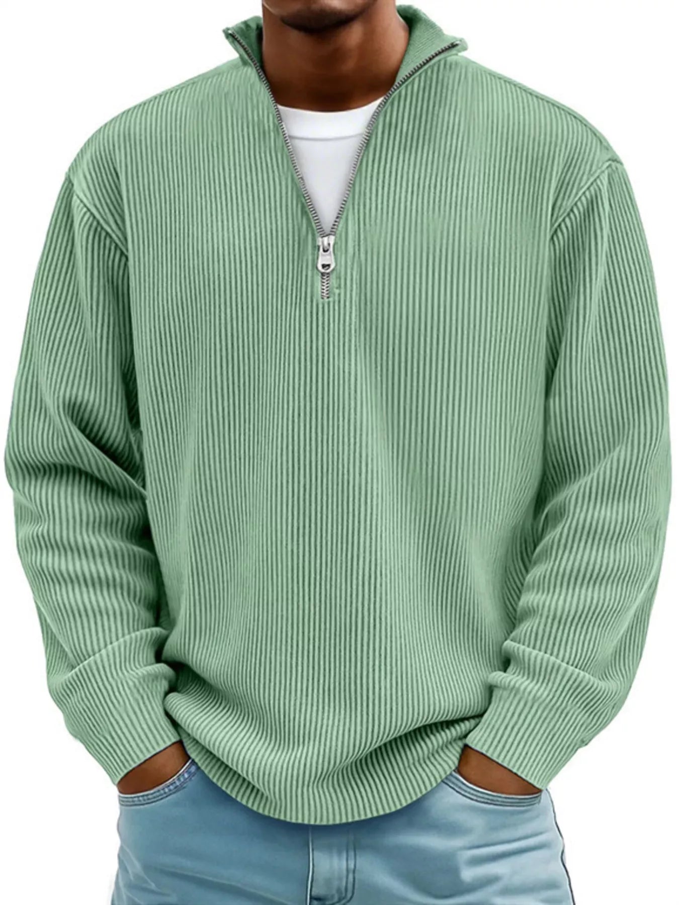 Man wearing a light green ribbed corduroy quarter zip pullover sweatshirt layered over a white shirt.