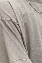 Woman wearing an oversized light gray Basic Bae round-neck half-sleeve T-shirt styled with dark denim jeans and a long pendant necklace for a relaxed, casual look.