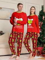 Man and woman modeling matching red Grinch-themed Christmas pajamas with festive graphic tops and red and black character-print pants.