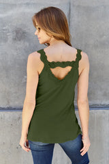 Woman wearing a matcha green colored Basic Bae lace-detail V-neck cami with delicate lace trim and cutout accents, styled with dark-wash jeans for a chic casual look.