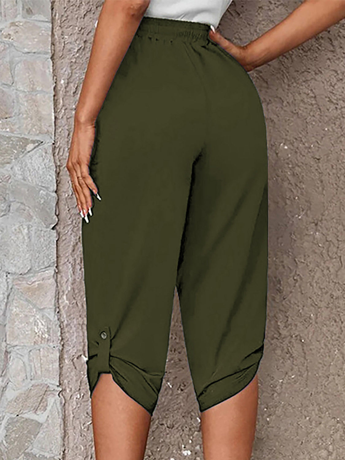 Model wearing matcha green roll-tab capri pants with side pockets and white sneakers for a casual outdoor look.